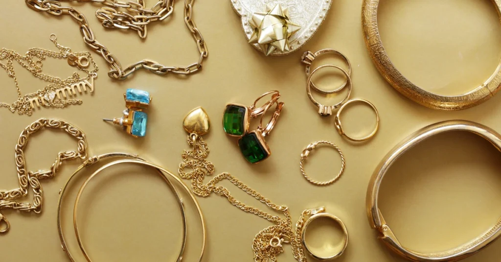 A collection of jewelry pieces, including rings, bracelets, necklaces, and earrings, displayed on a light-colored surface, highlighting their polished finish and variety of designs.