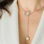 Close-up of stainless steel necklace with circular pendant and pearl drop