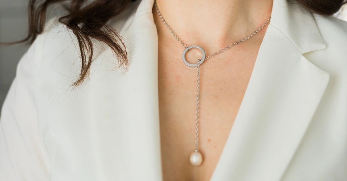 Close-up of stainless steel necklace with circular pendant and pearl drop